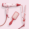 A set of hair styling tools including a hair dryer, straightener, and paddle brush, all with a cherry print design in red and white.