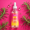 Bottle of Mark Hill The Hair Lab growth serum with rosemary leaves on a pink background
