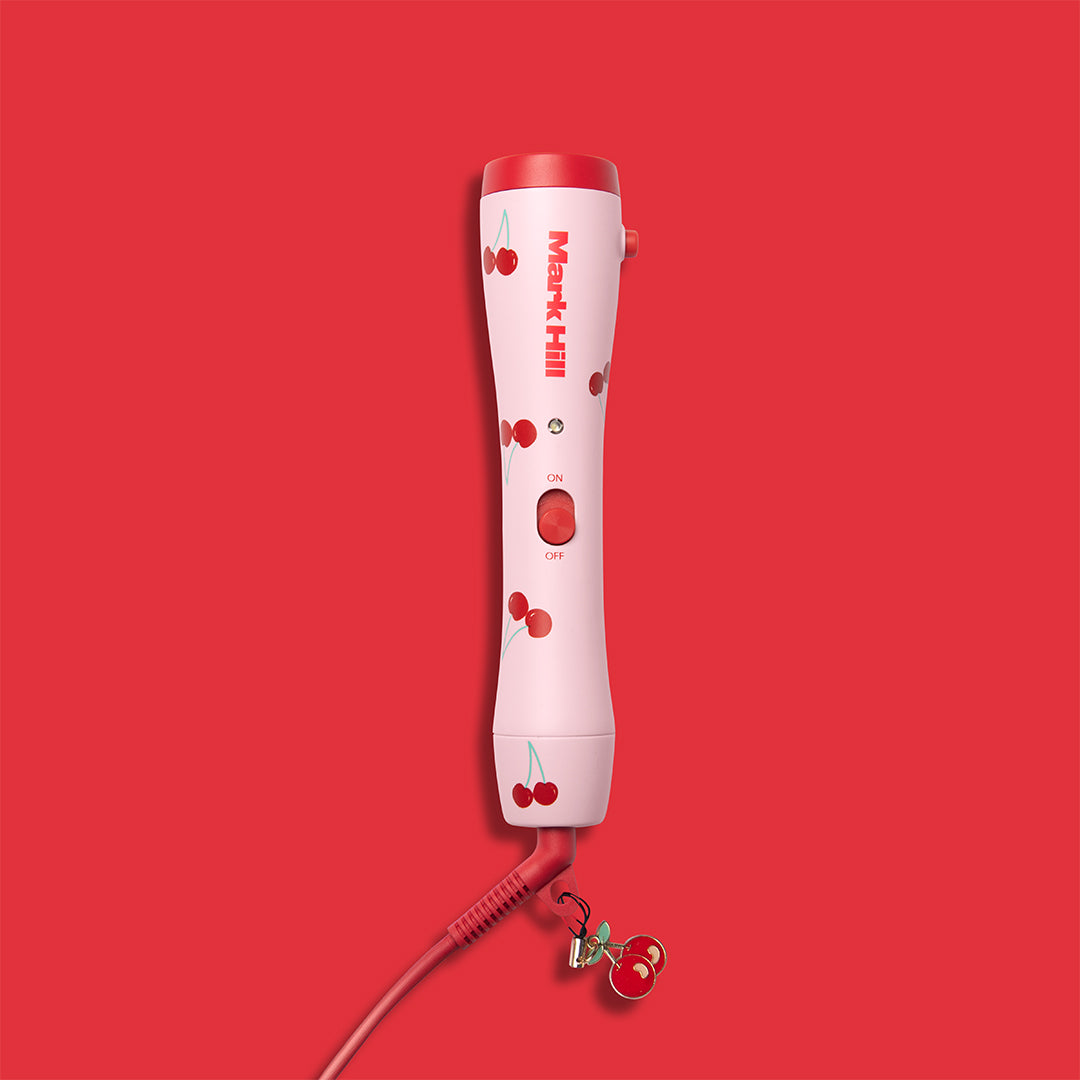 A red curling wand handle with a cherry print design, featuring a long cable and an on/off switch.